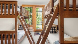 Un dormitorio con literas, una puerta de madera con ventana, y vistas a zonas verdes.