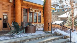 Un edificio de madera con un letrero que dice "VET BEER" y una chimenea. Hay sillas Adirondack afuera y un muro de piedra.