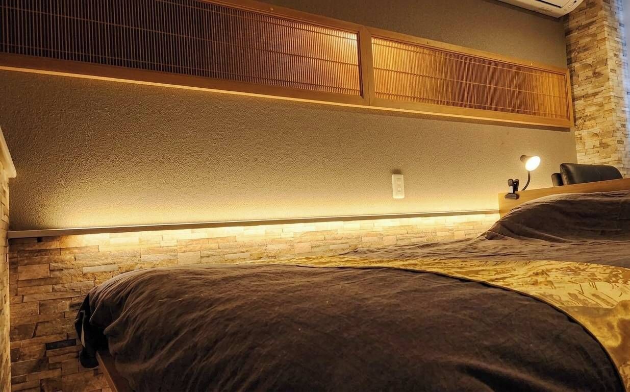 A hotel room with a bed, a nightstand, a lamp, and a wall-mounted shelf.