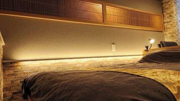 A hotel room with a bed, a nightstand, a lamp, and a wall-mounted shelf.