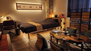Een slaapkamer met een bed, bureau, stoel en een bijzettafeltje met een decoratief object.