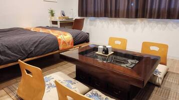 A modern hotel room with a bed, a dining table, chairs, a sofa, a small desk, and a window with curtains.