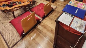 Een woonkamer met een zithoek, een televisie, een houten kast en een eethoek met een tafel en stoelen.