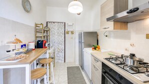 A modern kitchen with a stainless steel refrigerator, gas stove, and wooden bar counter.