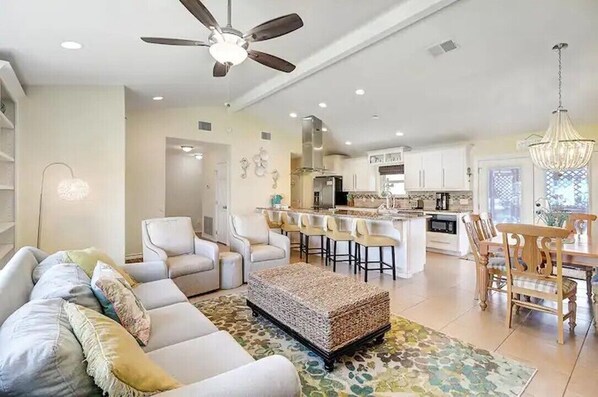 A modern living room with a sofa, ottoman, and dining area with chairs and a table.