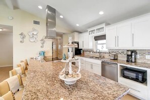 A modern kitchen with white cabinets, granite countertops, and a central island with decorative items. - Key Allegro Coastal Serenity! Private Hot Tub! Walking distance to Ocean!  (Rockport)