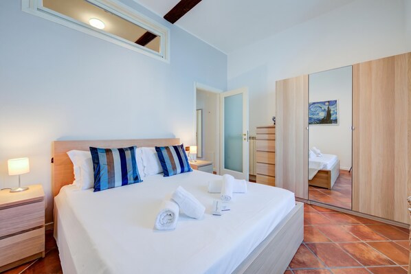 A bedroom with a bed, nightstands, a mirror, and a wardrobe.