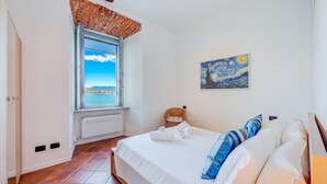 Un dormitorio con cama, ventana con vistas, un cuadro en la pared y un radiador.