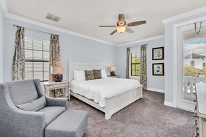 A bedroom with a bed, a chair, a nightstand, a ceiling fan, and a window with curtains. - Golden View | 5 BR, Themed Rooms, Game Room, West-Facing Pool (Kissimmee)
