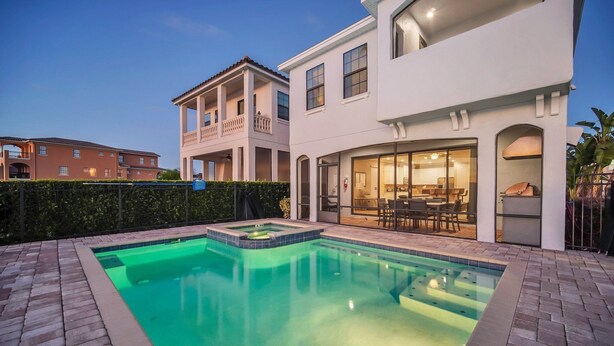 Una casa moderna con piscina, un patio con mobiliario exterior y un gran ventanal que da a un espacio interior.