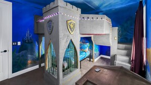 Una habitación con zona de juegos temática de castillo, que incluye una cama y una pequeña mesa.