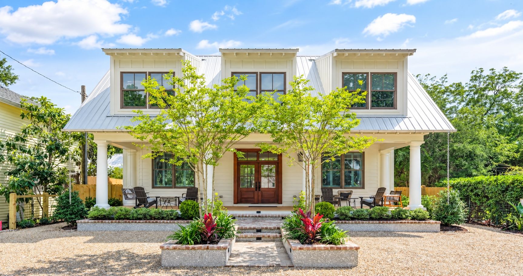 A two-story house with a covered porch, a front door, and a small garden area with plants and a pathway.
