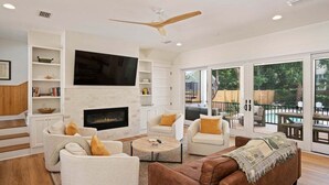 A modern living room with a fireplace, comfortable seating, and large windows offering a view of the outdoors.