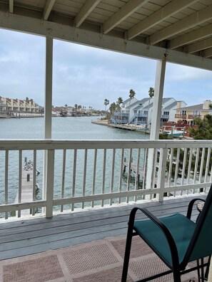 Eine überdachte Terrasse mit Blick auf eine Marina, Boote und Gebäude.