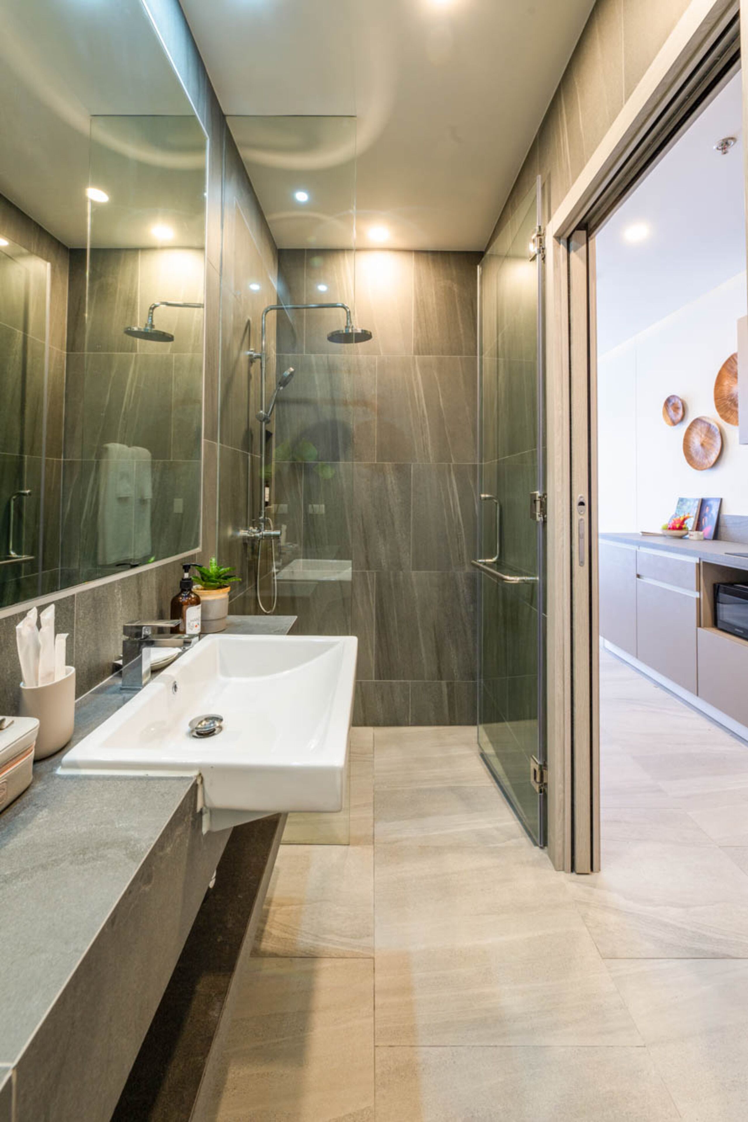 Un baño moderno con un espejo grande, un lavamanos blanco, cabina de ducha con mampara de cristal y tocador con encimera.