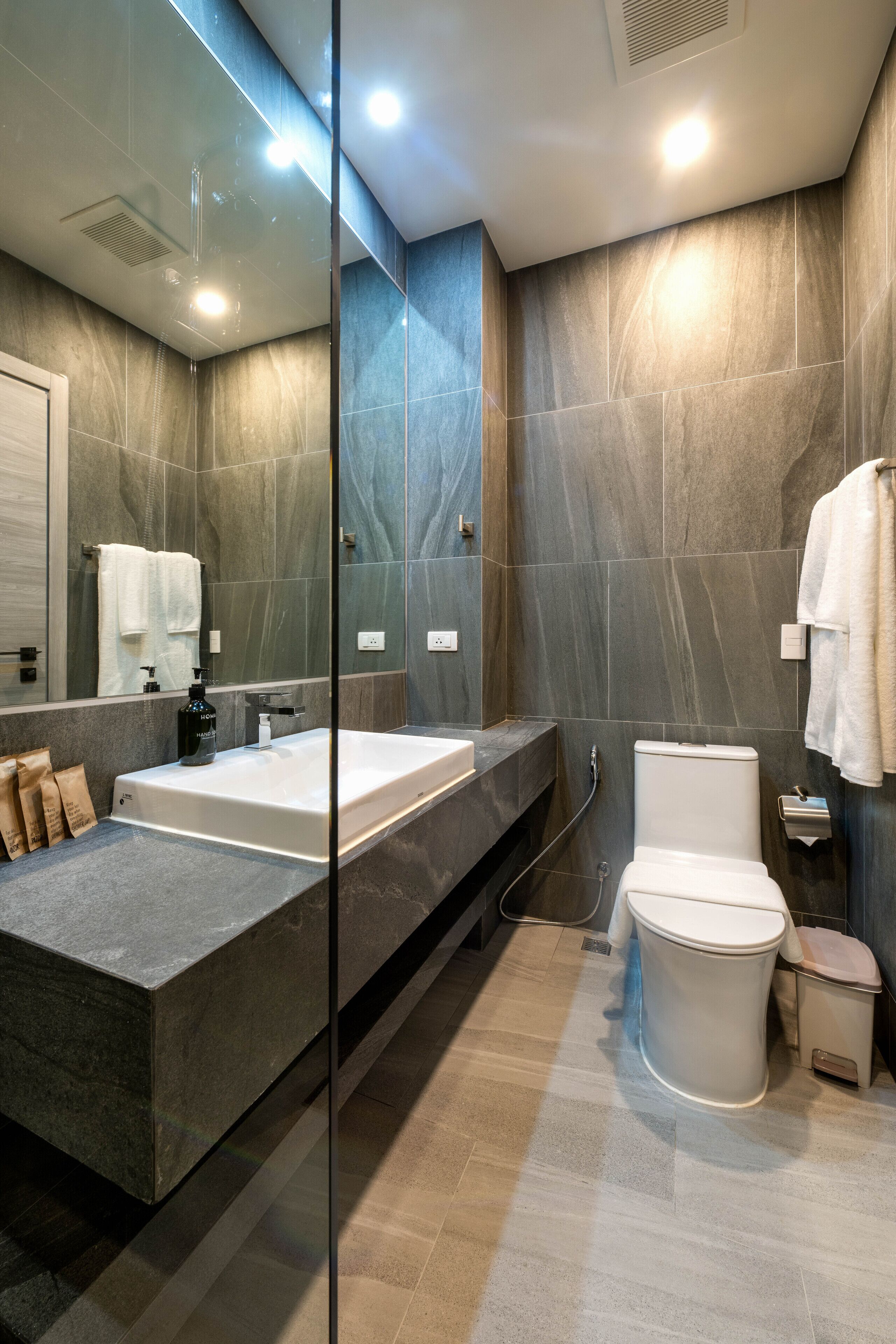 A modern bathroom with a large bathtub, a toilet, and a glass-enclosed shower area.