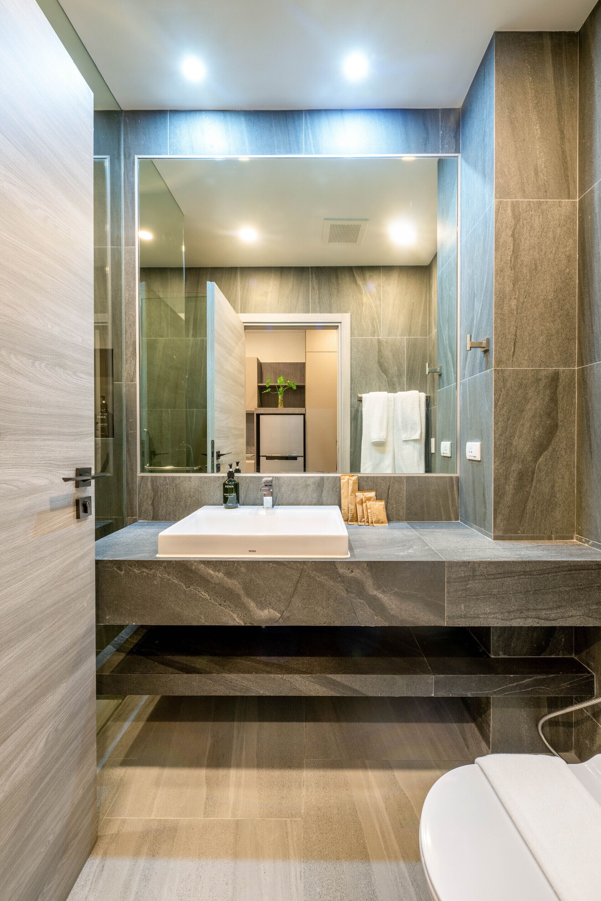 A modern bathroom with a large mirror, a white sink, and a glass shower enclosure.