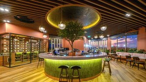 A modern bar area with a central island, bar stools, and a wooden floor. - HOMA Cherngtalay (Choeng Thale)