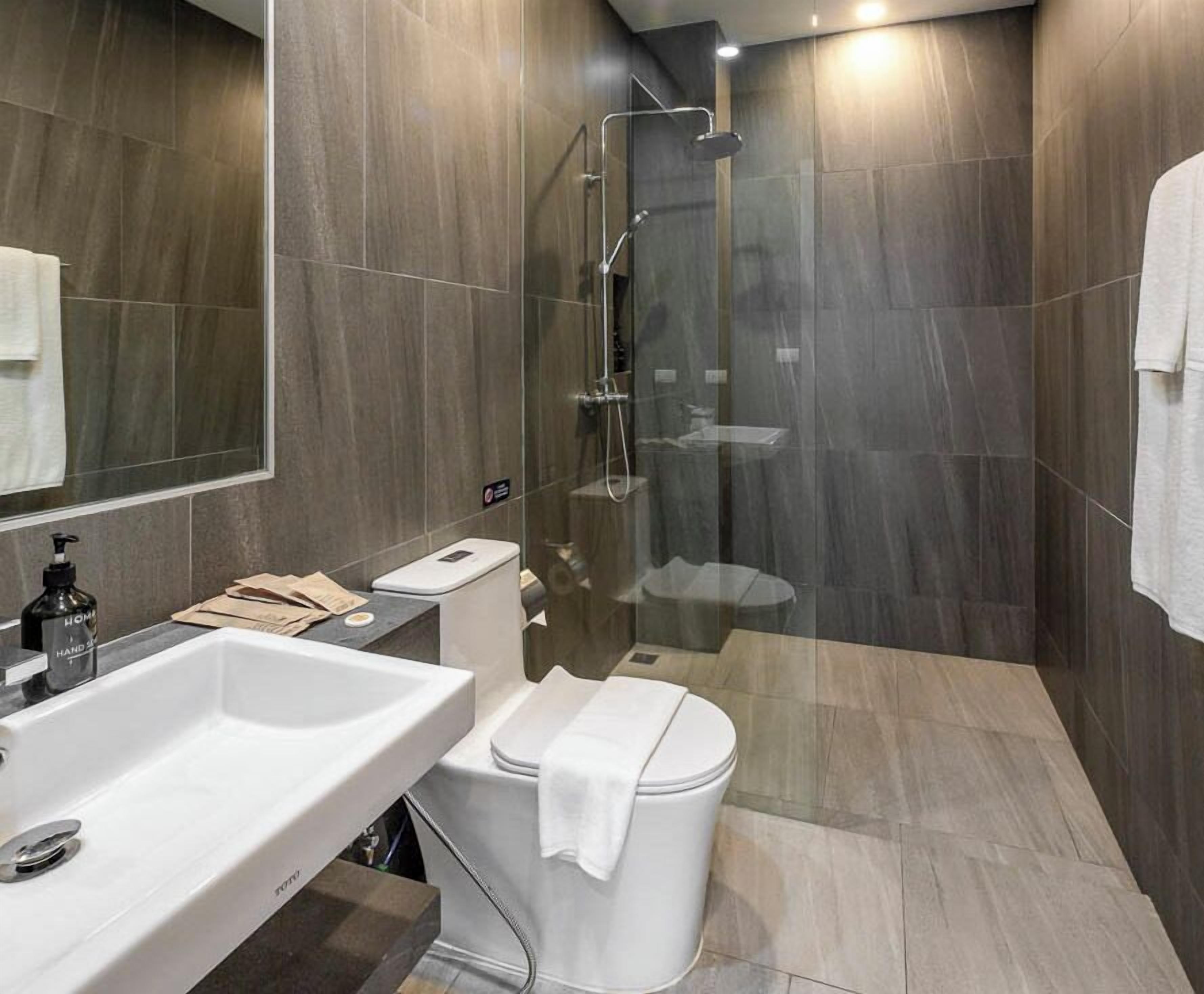 Ein modernes Badezimmer mit einem weißen Waschbecken, einer Toilette und einer Dusche.