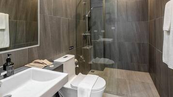 Ein modernes Badezimmer mit einem weißen Waschbecken, einer Toilette und einer Dusche.