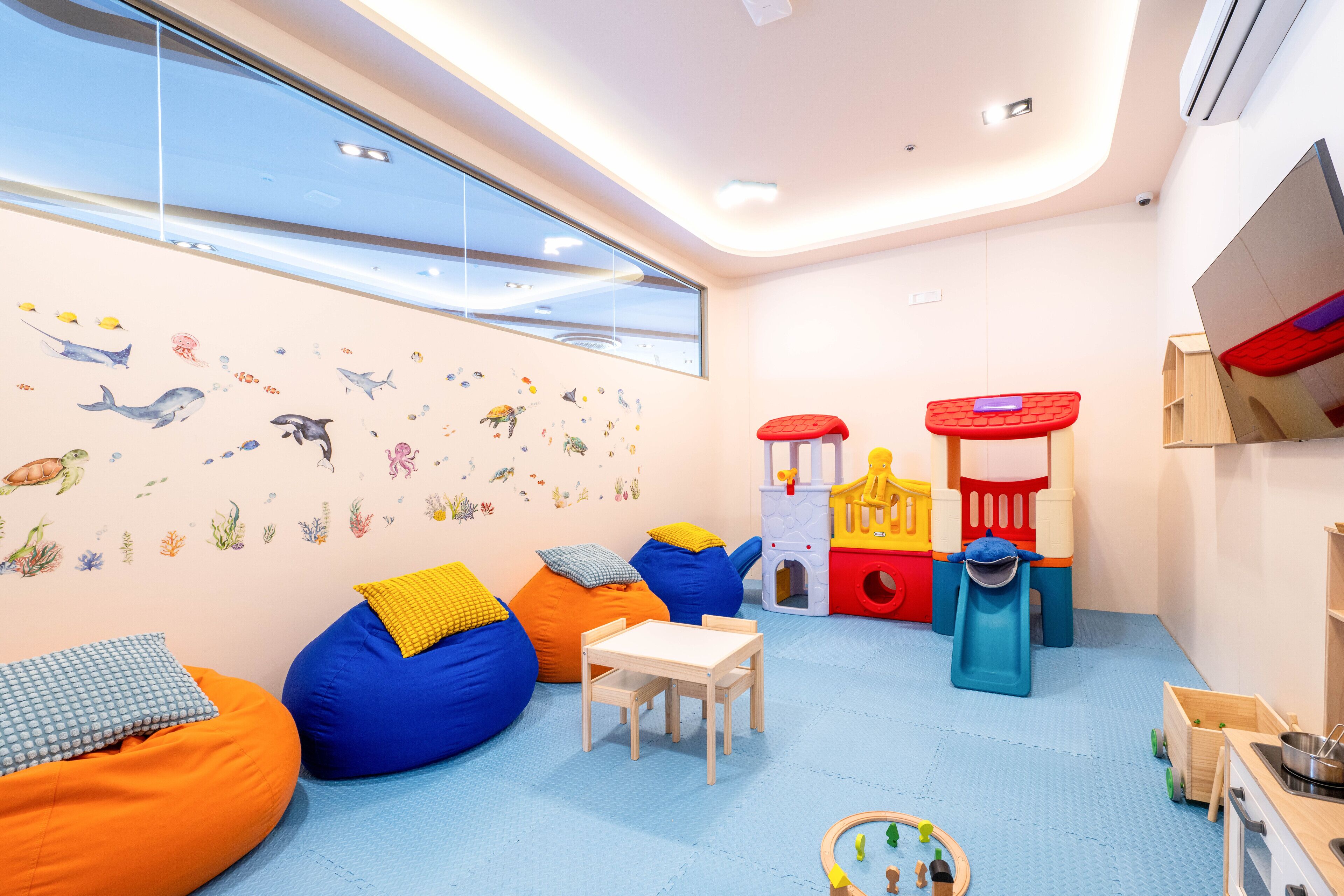 A children's playroom with bean bags, a playhouse, and a window with a view.