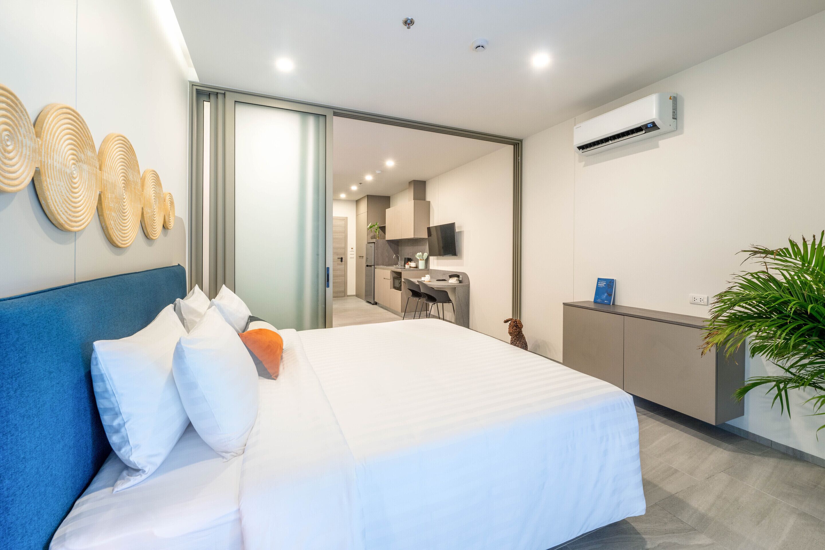 Una habitación de hotel moderna con una cama grande, un escritorio y una kitchenette.