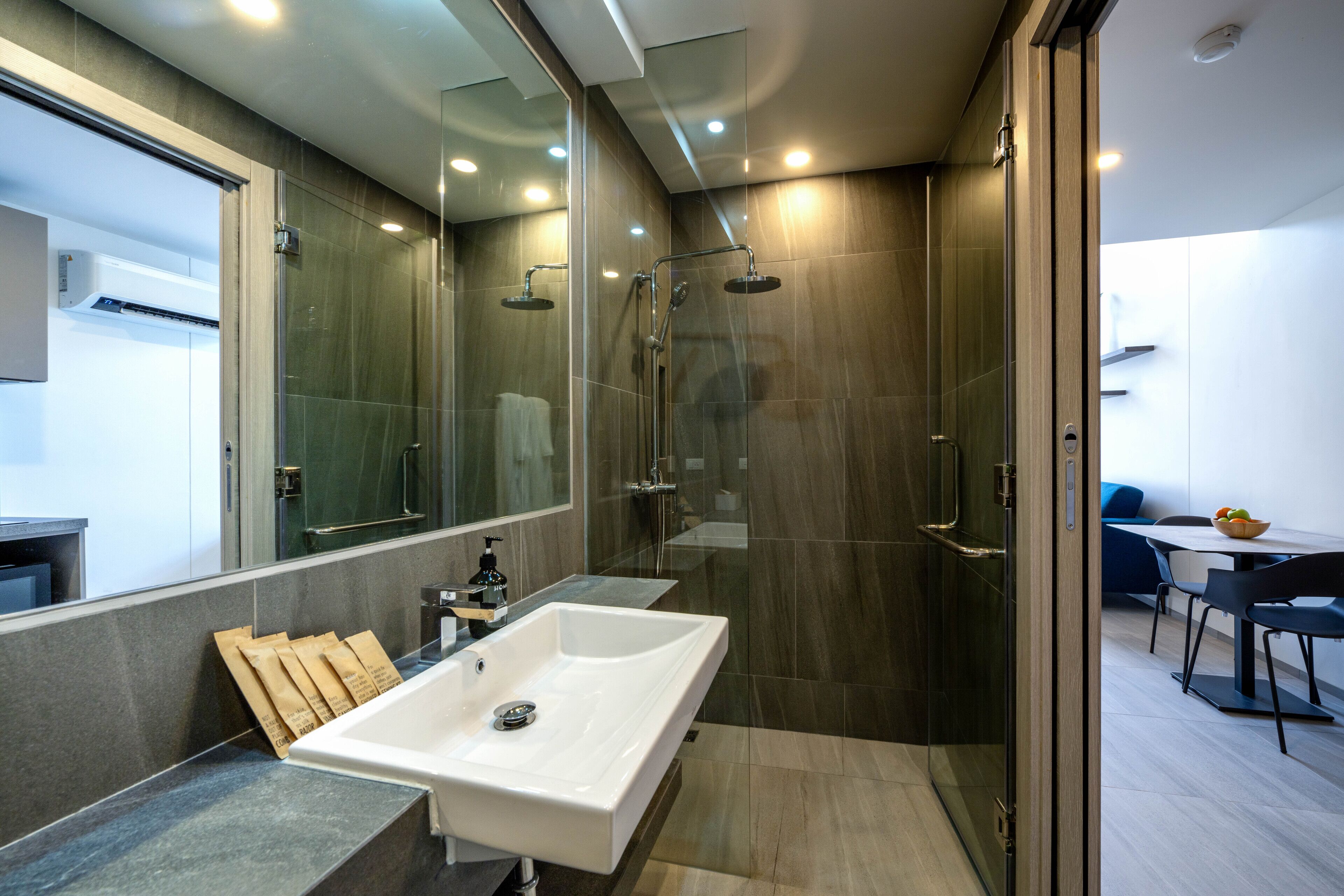 A modern bathroom with a large sink, a glass shower enclosure, and a mirror.