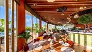 A modern restaurant with large windows, wooden ceiling, and a central bar area. - HOMA Cherngtalay (Choeng Thale)