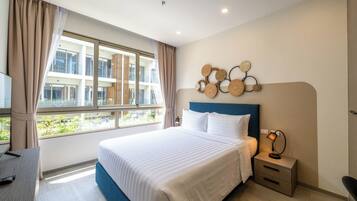 A modern hotel room with a large bed, a desk, and a window with curtains.