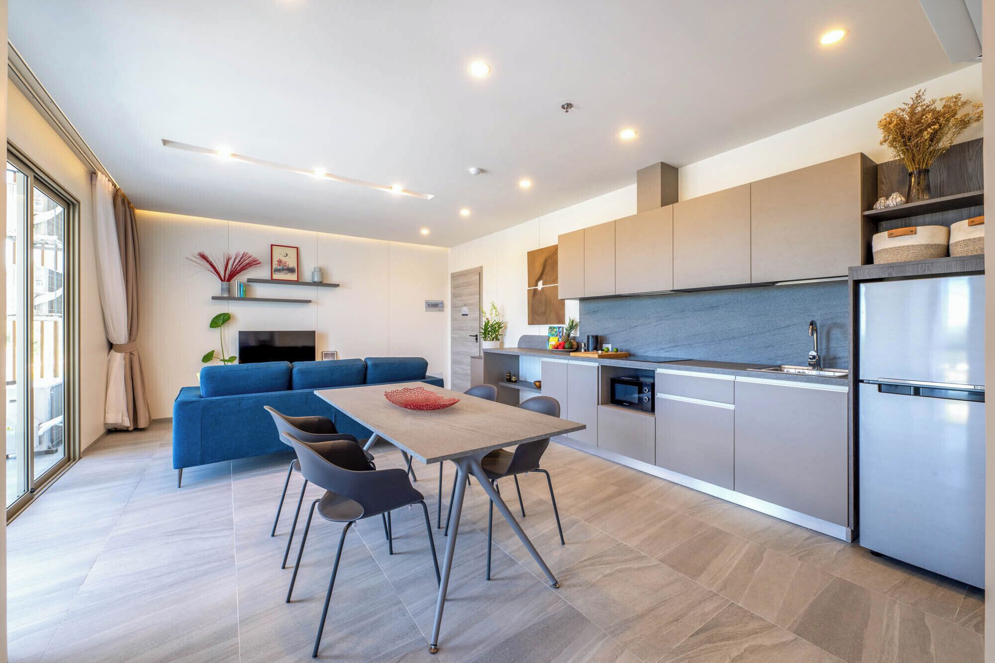 A modern kitchen with a built-in oven, a refrigerator, and a dining area with a table and chairs.