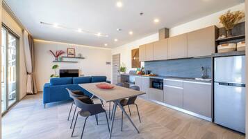 A modern kitchen with a built-in oven, a refrigerator, and a dining area with a table and chairs.