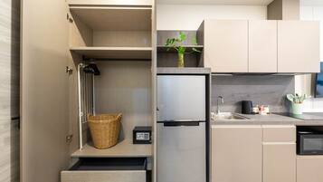 A modern kitchen with a built-in refrigerator, a microwave, and a sink. There is a basket on the countertop and a small plant on the shelf.