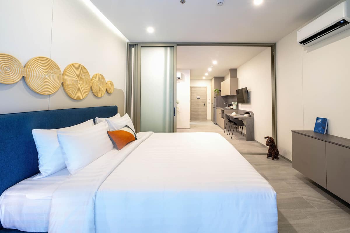 Une chambre d’hôtel moderne équipée d’un grand lit, d’un bureau et d’une kitchenette.