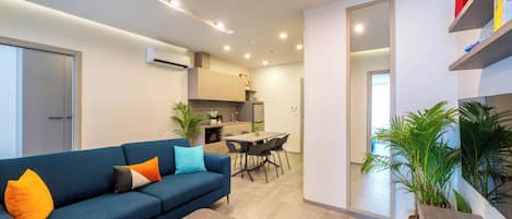 A modern living room with a sofa, coffee table, and a dining area with chairs.