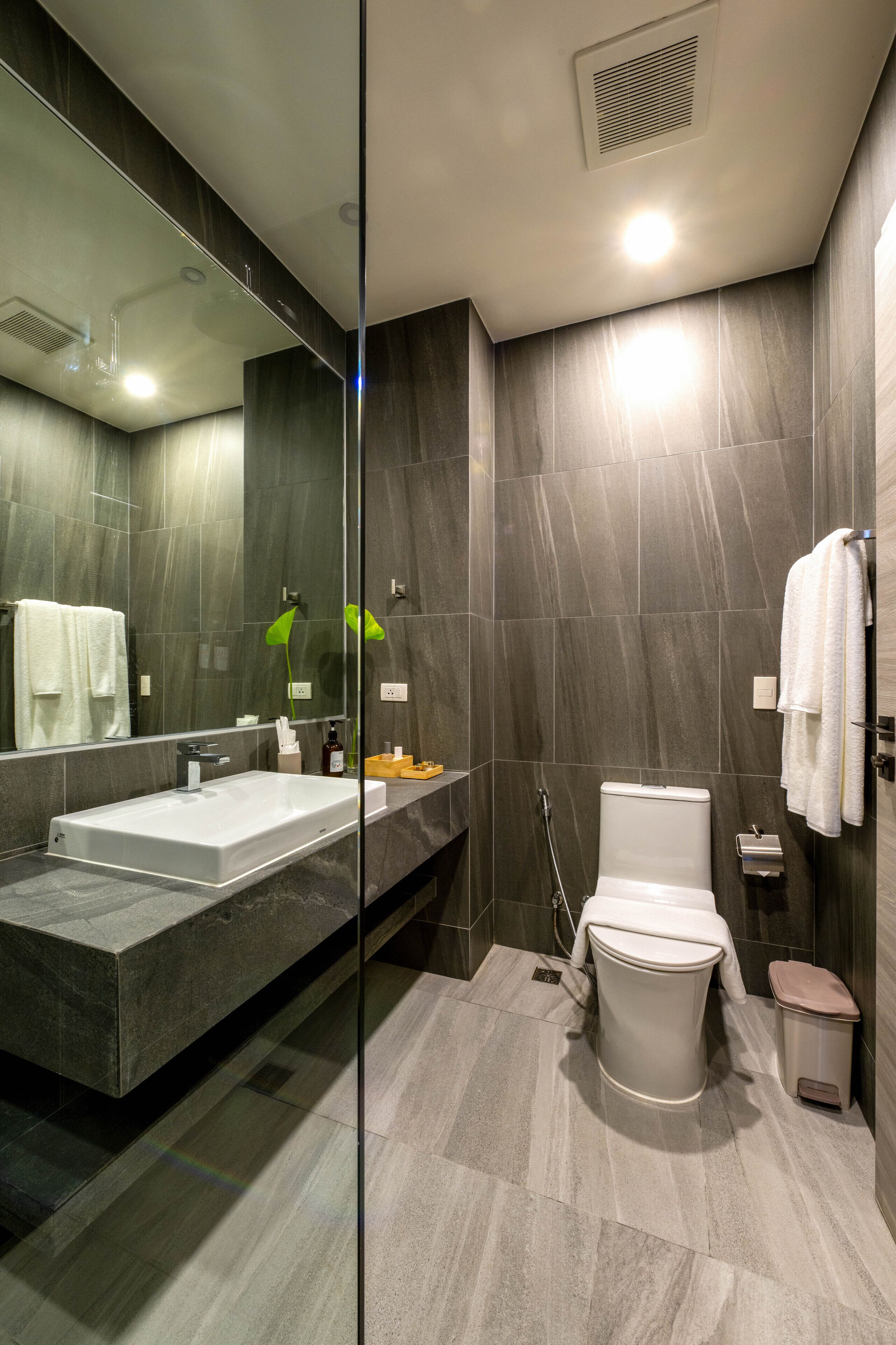 Een moderne badkamer met een wastafel met glazen ombouw, een toilet en een douchehoek.