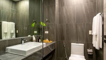 Een moderne badkamer met een wastafel met glazen ombouw, een toilet en een douchehoek.