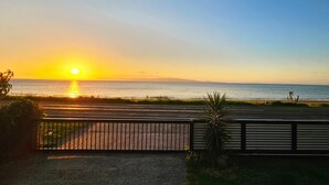 Une vue sur le coucher de soleil, prise depuis un espace clos, avec une route menant à la plage.