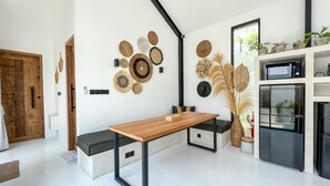 A modern kitchen with a wooden table, black metal frame, and a variety of decorative plates on the wall. - KAKAO Villas Kedungu (Tabanan)