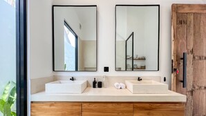Une salle de bain moderne avec deux vasques, des meubles en bois et de grands miroirs.