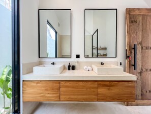 A modern bathroom with two sinks, wooden cabinets, and large mirrors.