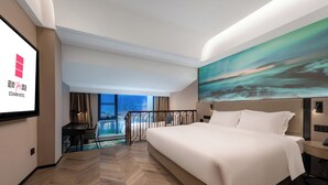 Habitación de hotel moderna con una cama grande, un escritorio y vistas a un paisaje urbano a través de amplios ventanales.
