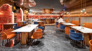 Un interior de restaurante moderno con paredes curvas, una zona de bar y asientos con sillas originales.