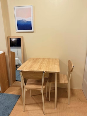 A room with a wooden table and chairs, a framed picture on the wall, and a door leading to another room.
