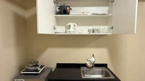 Una kitchenette compacta con refrigerador integrado, un lavamanos y una encimera.