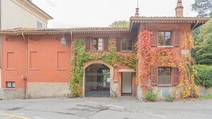 A building with a red facade, a gated entrance, and a small porch area. - La Piazza di Cernobbio (Cernobbio)