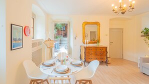 A dining area with a round table set for four, a mirror above the dresser, and a chandelier. - La Piazza di Cernobbio (Cernobbio)
