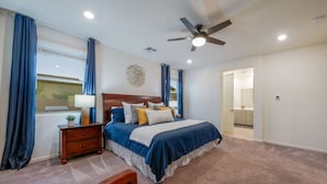 A bedroom with a bed, nightstand, lamp, and a ceiling fan.