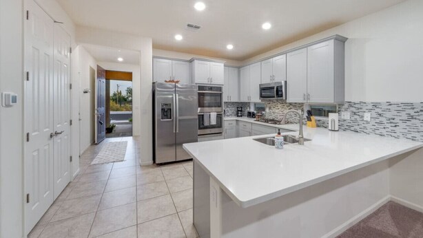 A modern kitchen with white cabinets, stainless steel appliances, and a large island with a sink.