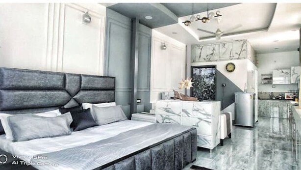 Une chambre à coucher moderne avec un grand lit, une console en marbre et une vue sur la cuisine.