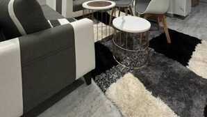 Un salon moderne comprenant un ensemble canapé, deux fauteuils, une petite table ronde et un téléviseur fixé au mur.